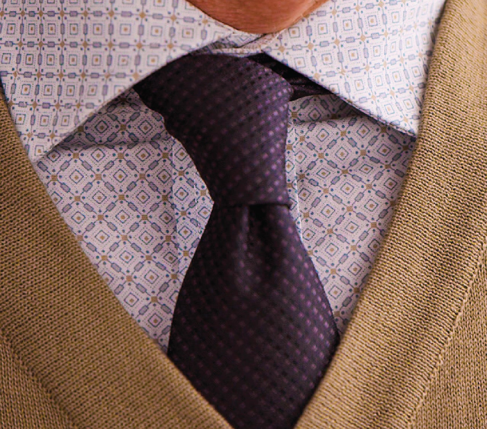 Close-up of a patterned shirt, tie, and vest with a geometric background